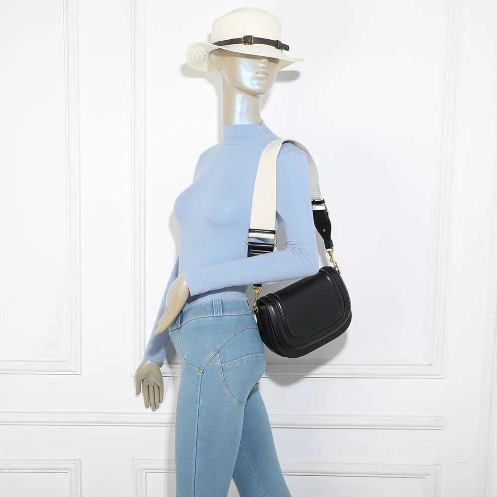 Sac Nova Loop noir porté par une femme, bandoulière large en tissu à l’épaule