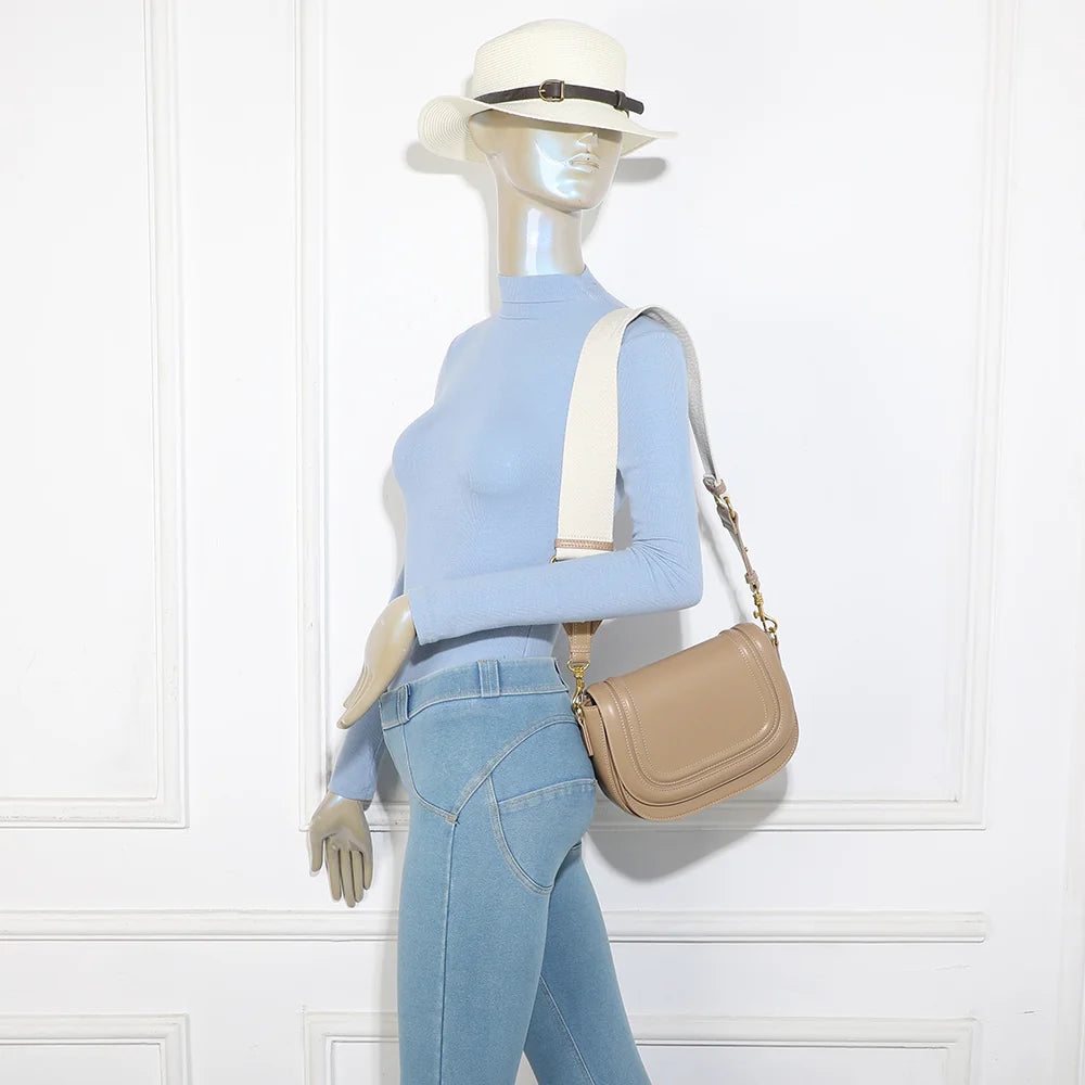Sac Nova Loop taupe porté par une femme, bandoulière large en tissu à l’épaule