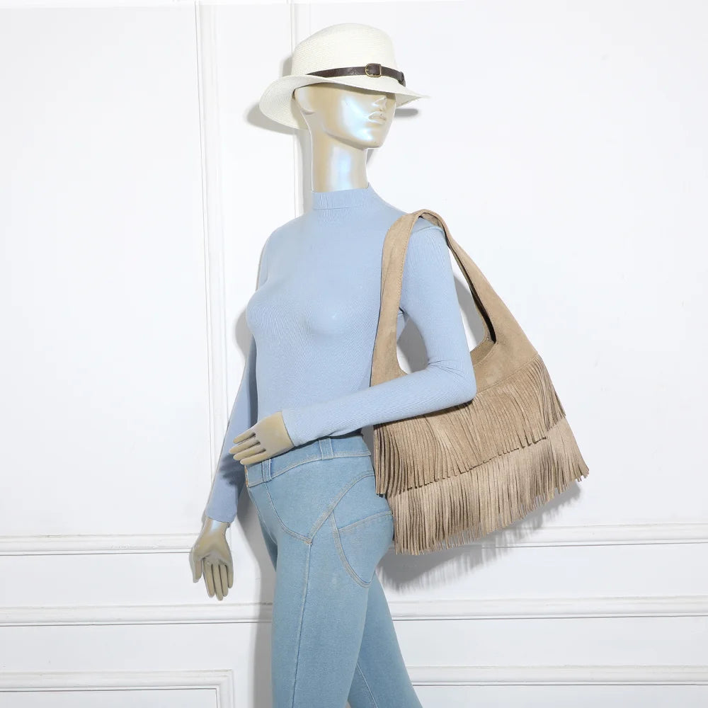 Sac hobo Ondaya taupe foncé porté à l’épaule par une femme, franges en mouvement au fil des pas – réf. M-9453