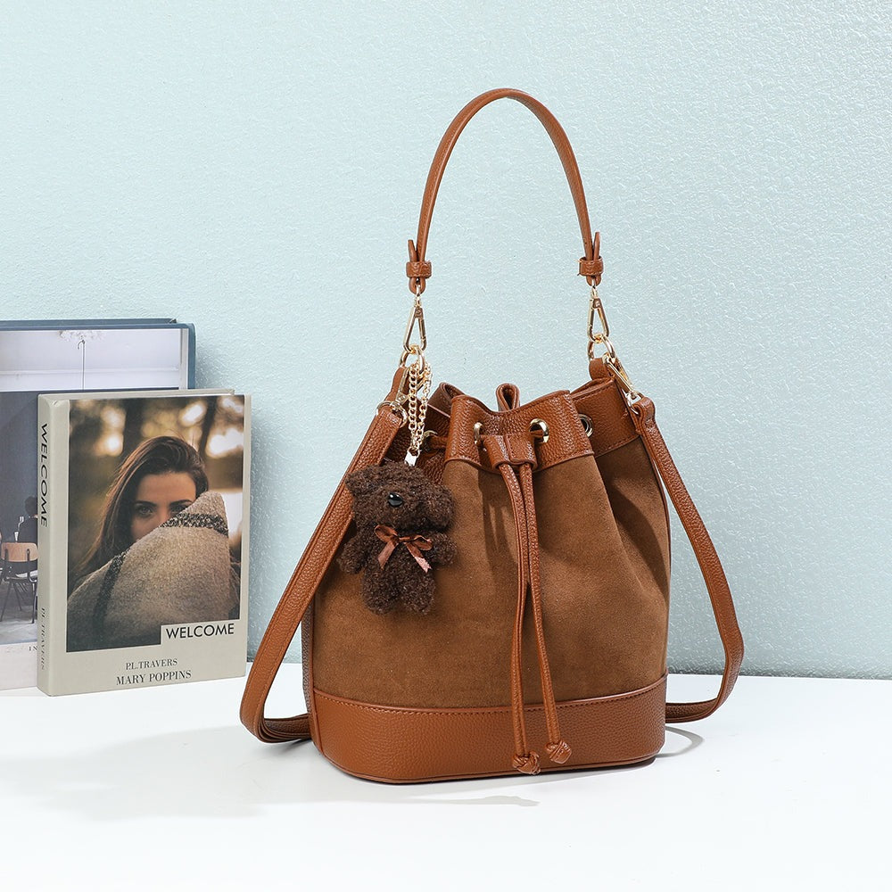 Sac seau Oria Suédine marron posé dans un décor, charm ourson et œillets dorés – visuel d’ambiance créé avec l’IA – Gallantry Paris