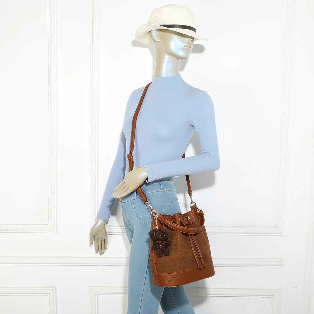 Sac seau Oria Suédine marron porté par une femme, en bandoulière réglable et amovible