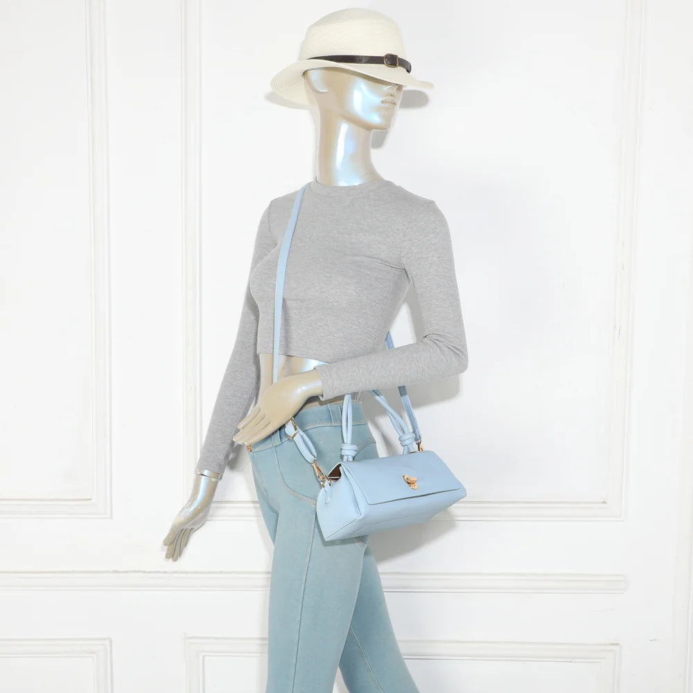 Sac Orlina bleu clair porté par une femme : format compact, à la main ou avec sa bandoulière amovible – réf. R-2048