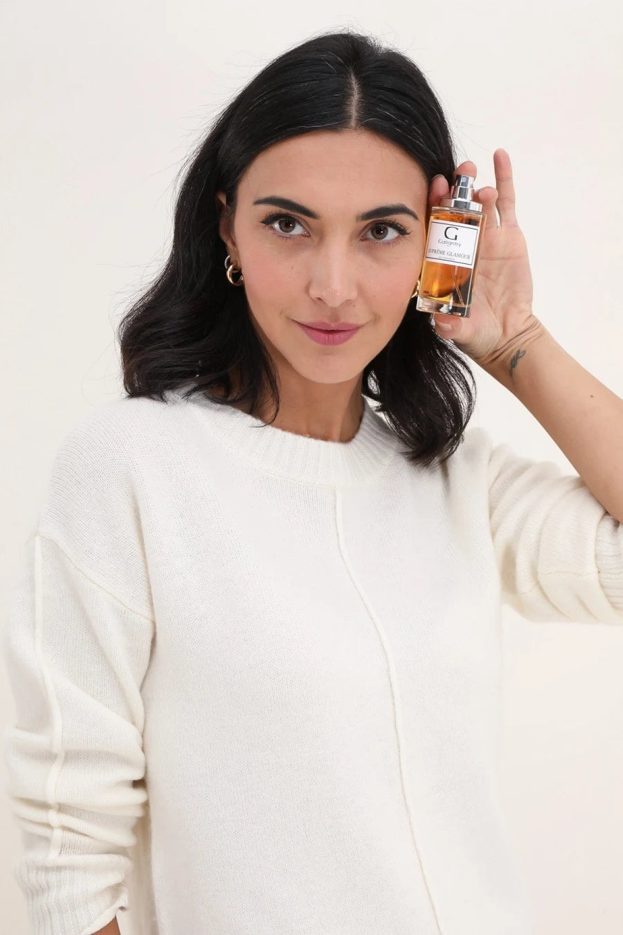 Femme vaporisant l'eau de parfum Suprême Glamour dans son cou avant une soirée