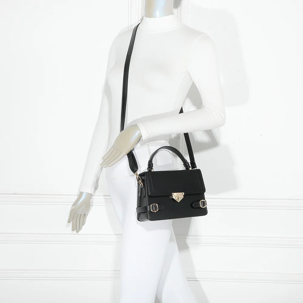 Petit Chic noir porté par une femme, un petit sac à main structuré avec ses boucles dorées – réf. C-0176-2