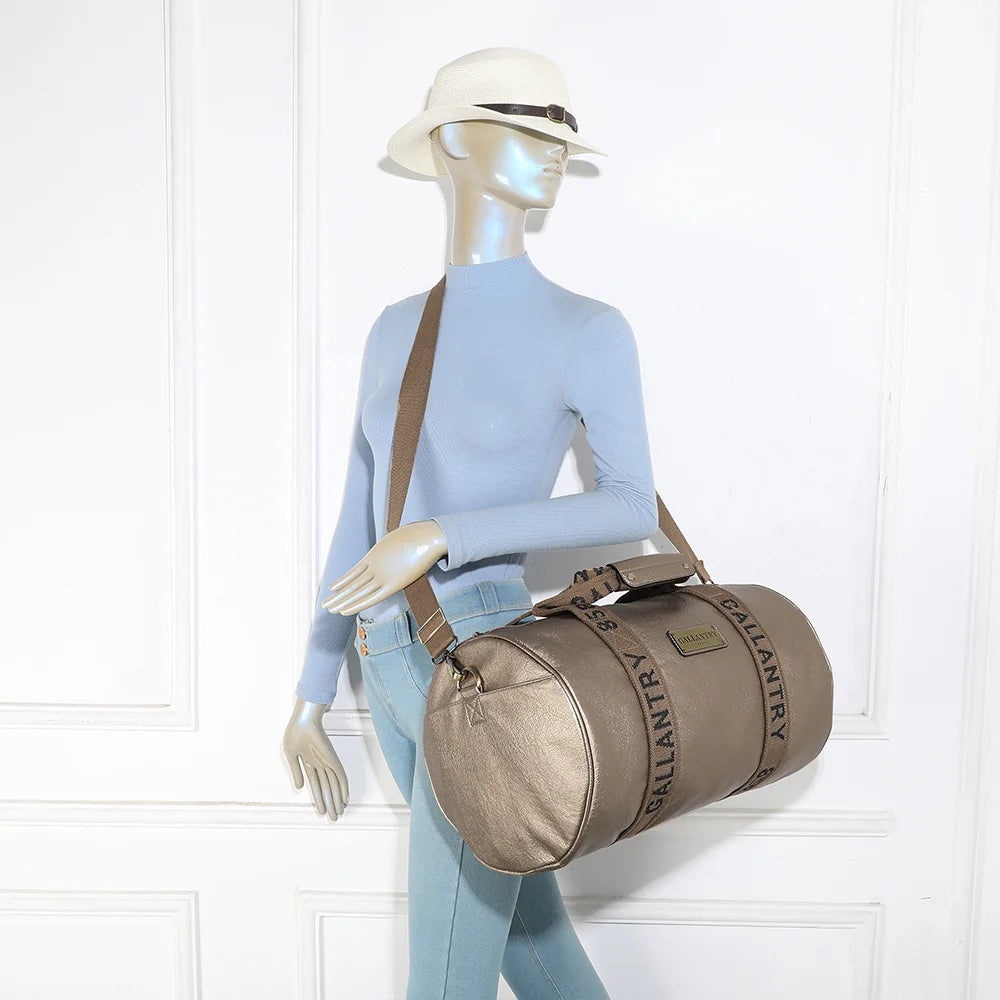 Sac de voyage Polochon or porté à l’épaule par une femme grâce à sa bandoulière amovible – réf. Z-83049