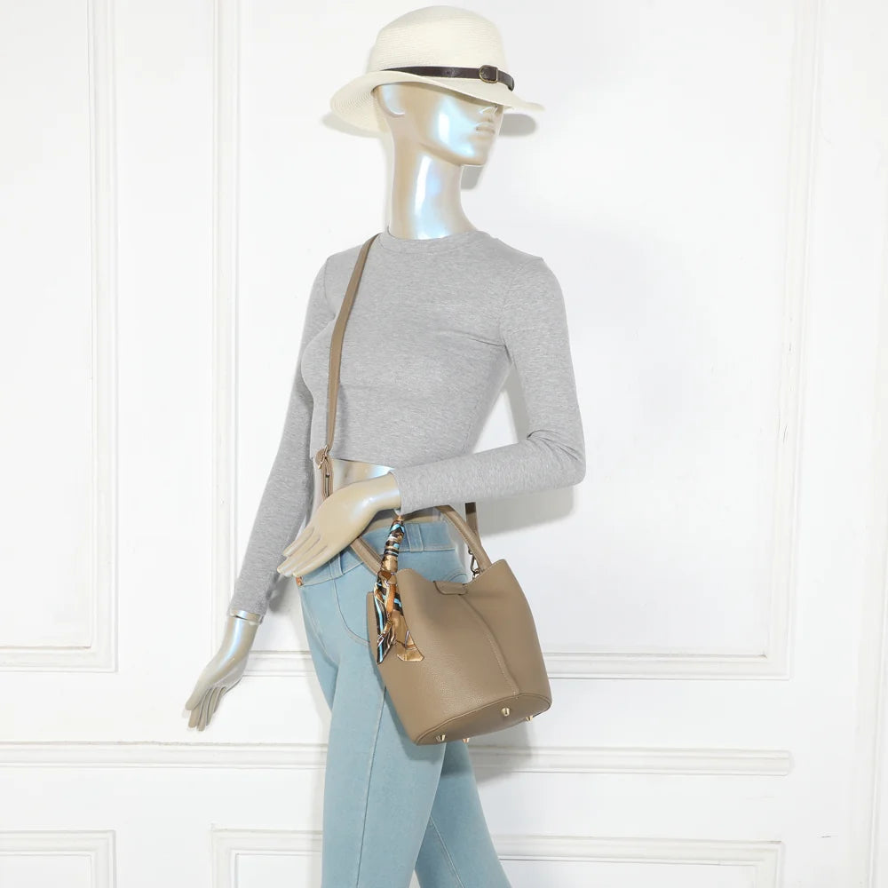 Sac Ruban Chic taupe foncé porté par une femme, à la main par son anse ornée d’un foulard – réf. KJ-62087