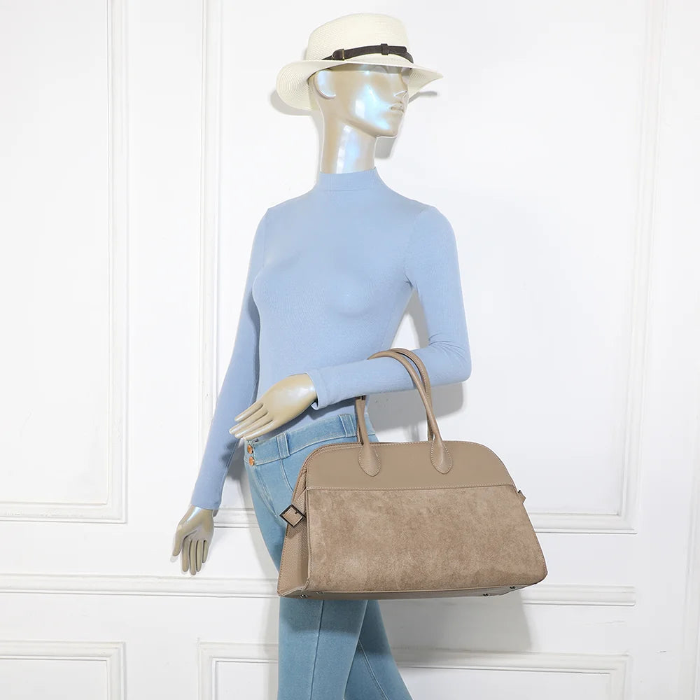 Sac Velna taupe foncé porté par une femme, à la main ou à l’épaule avec sa bandoulière amovible – réf. M-9444